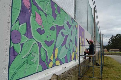 A artista plstica Doa Oa pinta un mural sobre a muller no Campo de Ftbol do Alivio